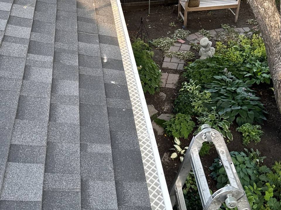 Gutter protection installed along a roof edge above a garden